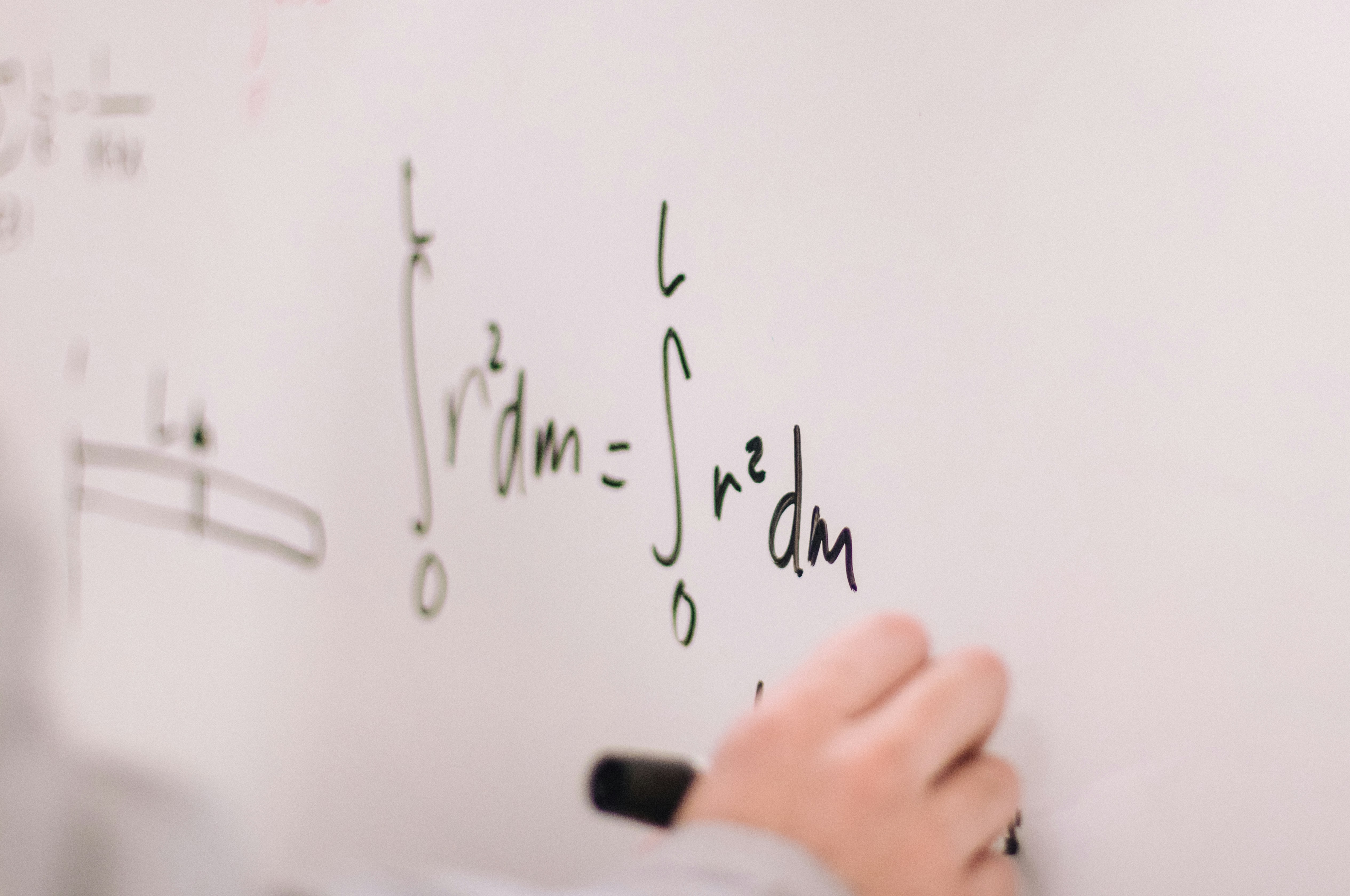 Tutor writing mathematics formulas on a whiteboard